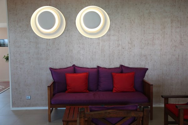 Recouvert de tissus Elitis, le canapé se détache visuellement du papier peint métallique Arte. Appliques Bahia, chez Foscarini.