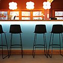 A la fois intérieur et extérieur, le bar, épuré, mélange de matériaux contemporains et nobles avec son comptoir en bois massif s'ouvre sur l'extérieur, en rappel de l'horizon...Tabourets, Moda International. Suspensions Next.