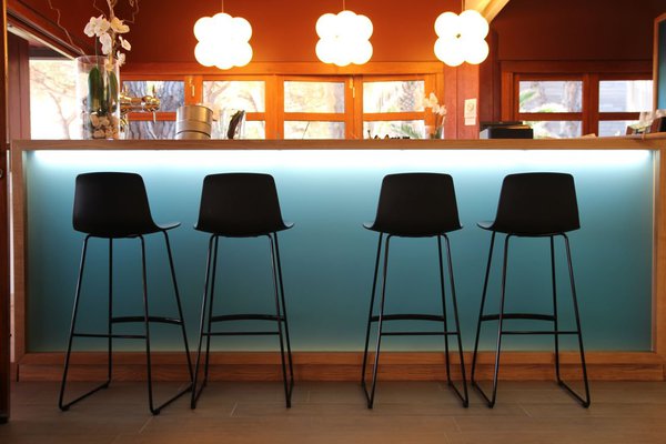 A la fois intérieur et extérieur, le bar, épuré, mélange de matériaux contemporains et nobles avec son comptoir en bois massif s'ouvre sur l'extérieur, en rappel de l'horizon...Tabourets, Moda International. Suspensions Next.