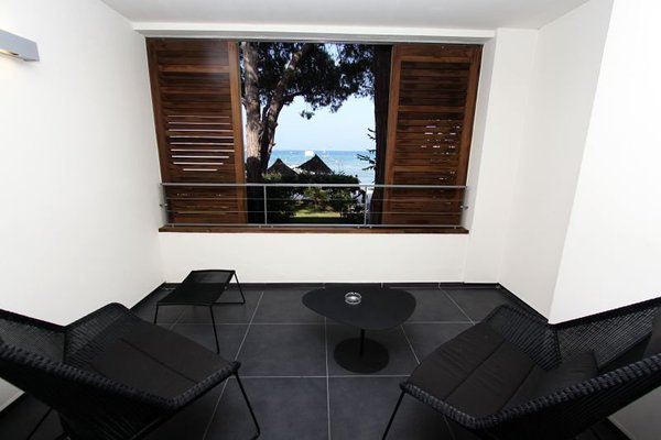 Avec un jeu de volets coulissants en bois, les loggias ont été aménagées dans un style indoor/outdoor comme des petits salons privés, équipés de fauteuils en maille tressée très souple, pour un confort enveloppant.