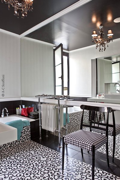 Une salle de bains, façon boudoir, aménagée comme une pièce à vivre  sur le thème du noir et blanc. Chaise à l’assise recouverte d’un motif pied-de-coq, chez Calligaris.