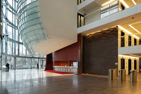 Lumière zénithale dans le hall principal de 20 mètres de haut se déploie derrière une paroi vitrée.