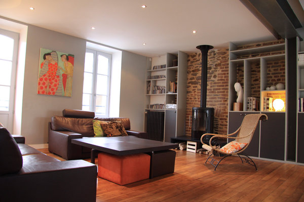 La partie salon, très cosy, donne, côté sud, sur la rue. Les fenêtres remplacées reprennent le modèle existant. Un poêle étanche rend l’espace encore plus convivial.