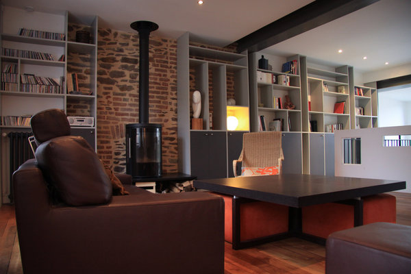 Le salon est bordé par une longue bibliothèque aux étagères sans fond qui laissent apparaître les murs de schiste et de brique datant de la construction.