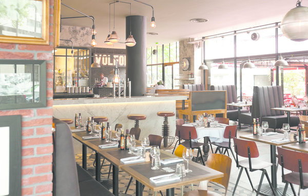 La grande salle lumineuse, son bar et au fond son comptoir à pizzas.