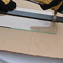 Etape 5 : Muni de gants, placer le coupe-verre à 2 mm à l’intérieur de la feuille de verre. L’outil devra être tenu bien perpendiculairement à la surface de coupe, et surtout bien pris en main.