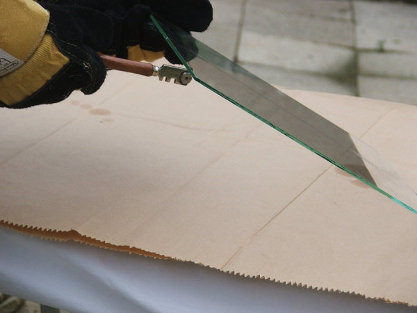 Etape 7 : Placer le coupe-verre partie métal sous le trait de coupe, et réaliser le détonnage, à savoir exercer de petits coups secs, sans trop taper fort pour autant, tout le long de la coupe, dans le but de faire filer la coupe, et ainsi pouvoir séparer les deux morceaux plus aisément.