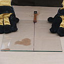 Etape 8 : Placer le talon de l’outil de coupe sous l’amorce du trait de coupe. Exercer une pression brève et ferme de part et d’autre de la feuille de verre, afin de scinder le verre sur toute sa longueur.