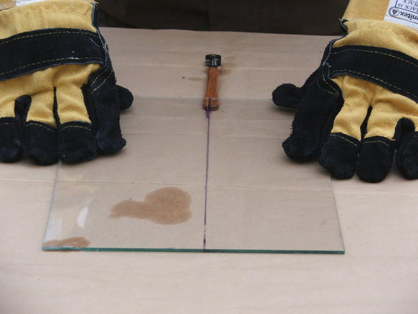 Etape 8 : Placer le talon de l’outil de coupe sous l’amorce du trait de coupe. Exercer une pression brève et ferme de part et d’autre de la feuille de verre, afin de scinder le verre sur toute sa longueur.