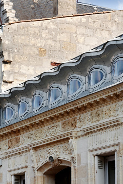 L’extension trace une sorte de « diadème qui se pose sur la corniche en pierre. Et le zinc (réalisation Vmzinc) dessine un petit masque vénitien.