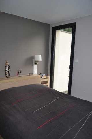 La chambre des parents, au rez-de-chaussée intègre une tête de lit qui fait office de rangement.