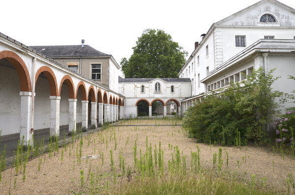 Galeries et bâtiments existants de l’hôpital Etoc Demazy, avec chapelle entourée d’arbres centenaires, espaces verts et multiples cours, bientôt valorisés.