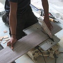 Etape 14 : Tenir la lame à pleines mains et passer le trait de coupe sous la lame de la scie circulaire sur banc. Le geste de poussée  doit être régulier, sans à-coups, et à vitesse constante.