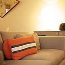 L’ancien canapé conservé a été re-houssé et se voit égayé par les couleurs vitaminées des coussins orange.