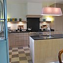 La cuisine au sol bicolore nappé d’un damier de pierre de Dordogne dessine un espace lumineux. Les éléments de rangement en plaquage de chêne cérusé et blanchi, ont été réalisés sur mesure. Leurs façades offrent des panneaux rainurés imitant un assemblage de planches massives. Le plan de travail est en granit.