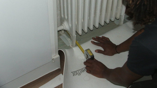 Etape 16 : Pour réaliser les découpes particulières comme autour des pieds de radiateur, effectuer en premier lieu la distance entre le mur et la longueur des pieds, puis reporter cette cote sur le dossier du revêtement.