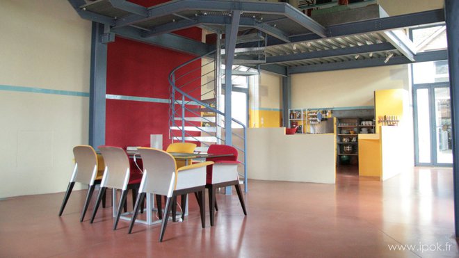 Cette grande pièce est conviviale et chaleureuse grâce au mélange des meubles colorés et du béton.