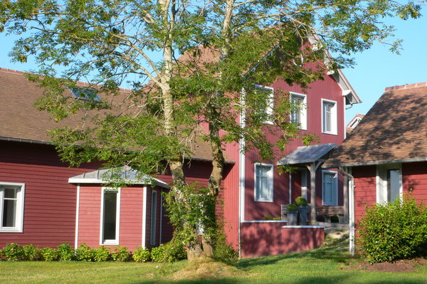 Cette maison en bois lasuré rouge évoque l’esprit des granges américaines et des maisons suédoises. Les espaces de vie sont rassemblés dans un seul volume, comme dans un loft, avec un effet de cathédrale éclairé par le haut. Un jeu de terrasses couvertes et découvertes renforcent le lien avec l’extérieur.