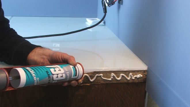 Etape 25 : Pose d’un cordon de colle en rive de plan de travail côté cuisson, destiné à recevoir une finition en tôle aluminium.