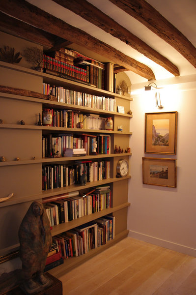 Comme un prolongement du salon, glissée entre les poutres, la bibliothèque trouve astucieusement sa place dans un recoin de l’appartement.