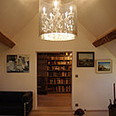 Le salon est habillé par un lustre monumental façon lanterne contemporaine. Il donne une impression de hauteur et met en valeur ce salon installé sous les toits.