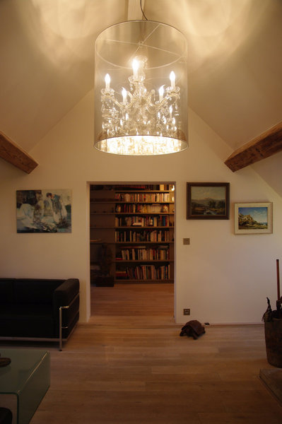 Le salon est habillé par un lustre monumental façon lanterne contemporaine. Il donne une impression de hauteur et met en valeur ce salon installé sous les toits.