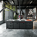 L’îlot de cuisine Minà s’insère et s’accorde parfaitement à ce loft au sol en béton ciré. Les deux grandes hottes flexibles Mammut, faisant figure de robots, y apportent une touche quasi-futuriste.