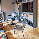 Un ancien fauteuil de salon de coiffure et un siège en grillage métallique de récupération font face au canapé de lignes contemporaines. Le rangement mural qui accueille l’écran de la TV a été conçu et réalisé sur mesure (Huggy).
