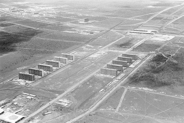 Lorsque les travaux commencent en 1956, le Planalto Central est envahi par plus de 60 000 « candangos », les ouvriers bâtisseurs de la future Brasilia. Mario Fontenelle offre ici une vue aérienne de l’esplanade des ministères, à l’est la construction du Congrès National, et à l’ouest la gare routière de Brasilia.