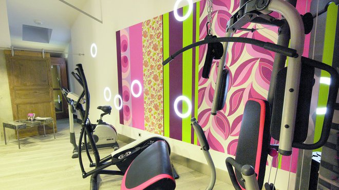 Dans la salle de sport, on retrouve les mêmes codes graphiques : papiers peints déclinés dans une gamme de couleurs particulières, et éclairage singulier façon « donuts », création Modular. Dans la salle de sport, on retrouve les mêmes codes graphiques : papiers peints déclinés dans une gamme de couleurs particulières, et éclairage singulier façon « donuts », création Modular.