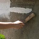 Etape 14 : A l’aide d’une brosse métallique, enlever les grains du mortier de ciment de l’ensemble du mur. Bien insister avec l’outil ; cela permettra à la peinture de bien adhérer par la suite.