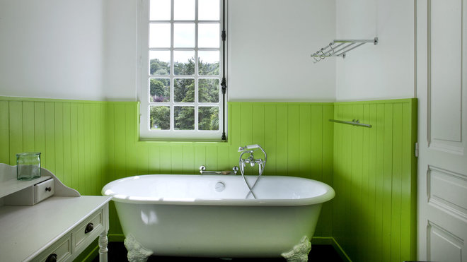 Cette salle de bains, à la baignoire rétro et aux murs lambrissés, est modernisée par le choix de la couleur vert anis.