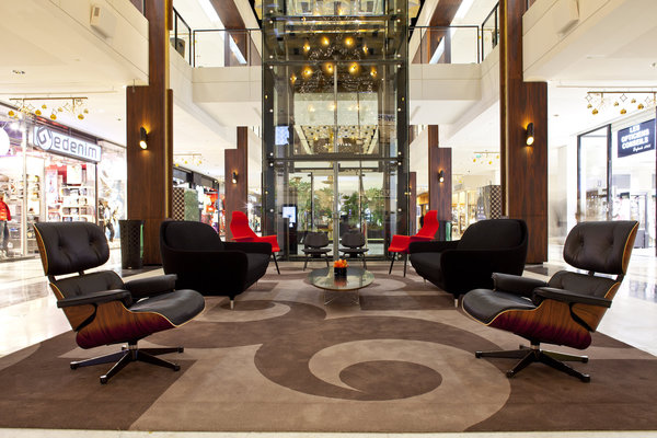 L’axe central est découvert, pour donner une impression d’espace, et constituer de véritables carrés lounge. Trois espaces de repos sont meublés par les designers des sixties. Ici on retrouve notamment le fauteuil Lounge Ray & Charles Eames, en cuir et noyer plywood, édité pour la première fois en 1956.