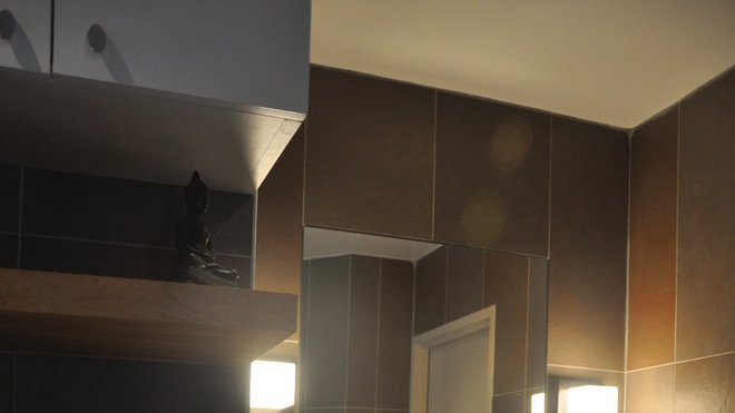 Une harmonie de tons bois et fumés habille de coin vasque. Le carrelage (Saloni) décline un dégradé de bruns jusqu’au kaki. Le format allongé posé à la verticale apporte une touche d’originalité.