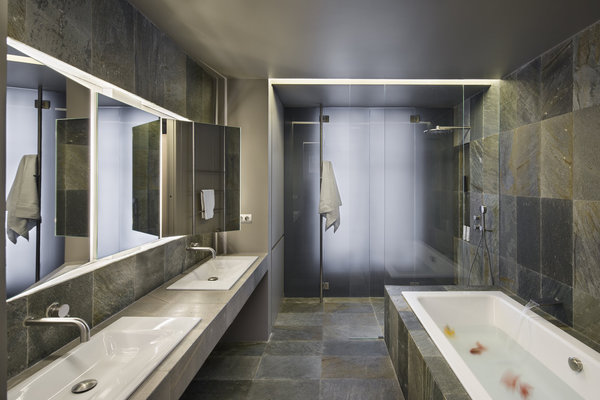 La salle de bains nappée d’un carrelage en pierre offre un autre exemple de l’utilisation d’un matériau naturel et authentique. Son élégance résulte de cette matière employée