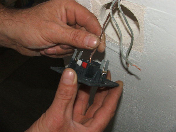 Etape 5 : Au dos de l’interrupteur clipsez le fil de phase dans son logement indiqué ; il n’est plus besoin de visser les fils avec les nouveaux modèles d’interrupteur.