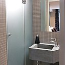 Dans cette micro salle de bain (2 m²), la vasque en béton a été réalisée sur mesure, avec un pan coupé, pour dégager un passage vers le coin toilettes.