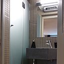 Le robinet a été installé, latéralement, pour ne pas gêner la circulation. La cabine de douche biseautée, à pan coupé,  permet d’épouser l’espace sans perdre de place. Carrelage en grès cérame, Winckelmans.