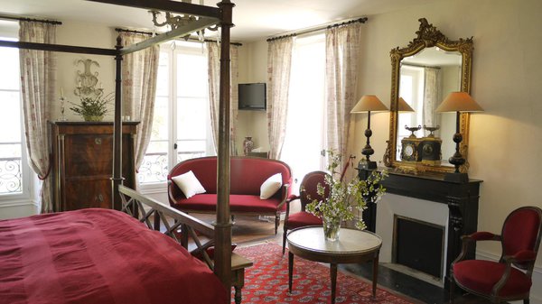 Raffinée et charmante, la chambre Maussion de Candé se décline dans des teintes rouges et beiges.