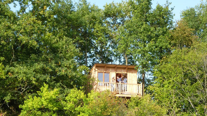 Cabane falaise qui enjambe la roche avec terrasse au-dessus d’un lac de carrière.