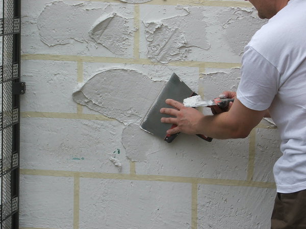 Etape 9 : A l’aide d’une lame à enduire, déposez des plots d’enduit de manière à créer les pierres. Variez sur l’épaisseur du dépôt d’enduit, afin d’obtenir des effets de matière plus ou moins prononcés.