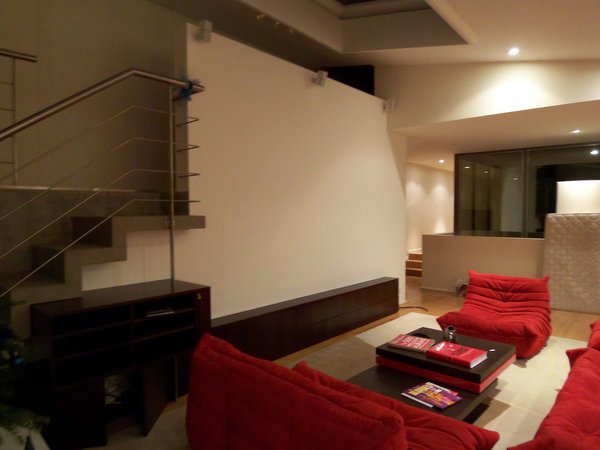 Le salon (fauteuils et canapés, modèle Togo, création Michel  Ducaroy pour Ligne Roset) occupe l’espace central du plateau aménagé sur une base de 200 m². L’escalier mène à la chambre des amis.