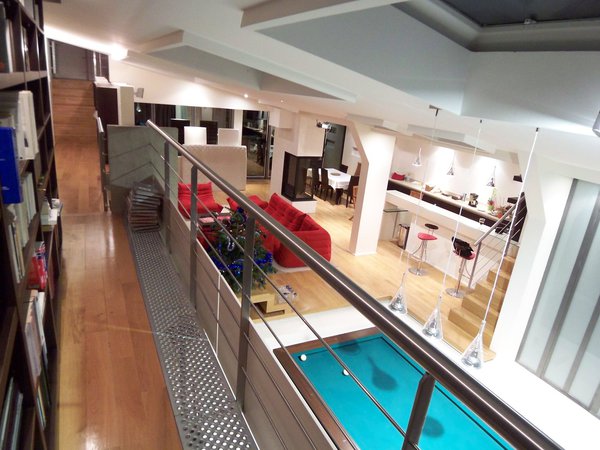 Grâce à la passerelle, on accède à la bibliothèque, mais aussi à un petit salon de lecture, situé à l’extrémité du couloir et qui surplombe le patio.