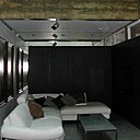 Appart 1. Au rez-de-chaussée, le salon aménagé sous la terrasse-patio profite de la lumière naturelle en hauteur. Un jeu de placards habille deux murs, et forme une alcôve qui s’ajoute aux tableaux organisés en triptyque.