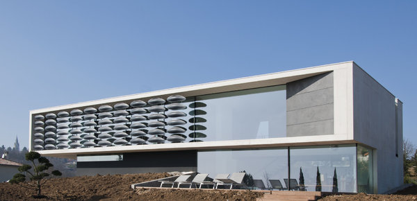 Ce volume en béton blanc avec façade de verre à faible émissivité est en partie protégé par un rideau de forme elliptique en Corian ® noir. Il permet de conserver, à l’intérieur, un cadre visuel maximum, tout en réduisant l’impact solaire. Maison BBC, chauffée par géothermie, équipée de rupteurs thermiques et d’une ventilation à double flux. Creation Au*M [Pierre Minassian], Chipster Blister House, 2012.