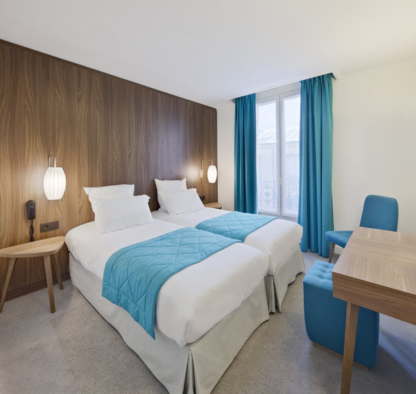 Le bleu azur crée une harmonie apaisante, réchauffée par la tête de lit king size qui occupe toute la surface du mur.