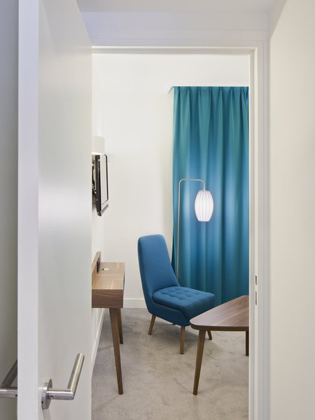 Petit fauteuil capitonné et lampadaire épuré signent un décor contemporain, délicieusement vintage.