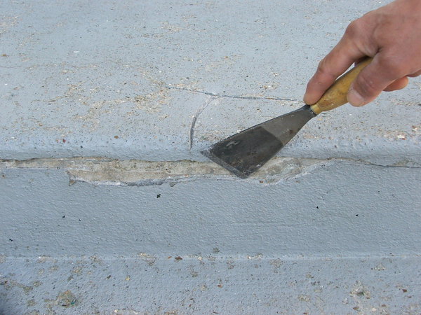 Etape 2 : A l’aide d’un riflard de maçon, éliminer tous les résidus de béton abîmés et non adhérents. Elargir les fissures apparentes ; bien insister avec l’outil.