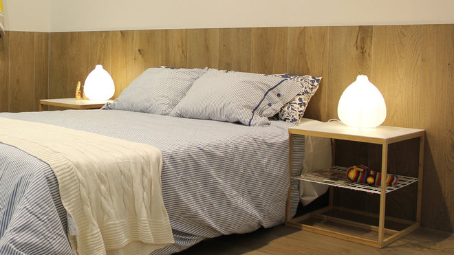 Original, le revêtement de sol en céramique, imitation bois, remonte sur le mur à mi-hauteur, pour former une tête de lit, et créer une atmosphère cosy. (Keraben, Madeira Titanium)