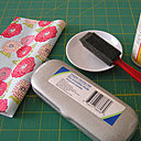 Il vous faut : un étui à lunettes, des tissus, un pinceau mousse, de la colle blanche et des rubans fins.